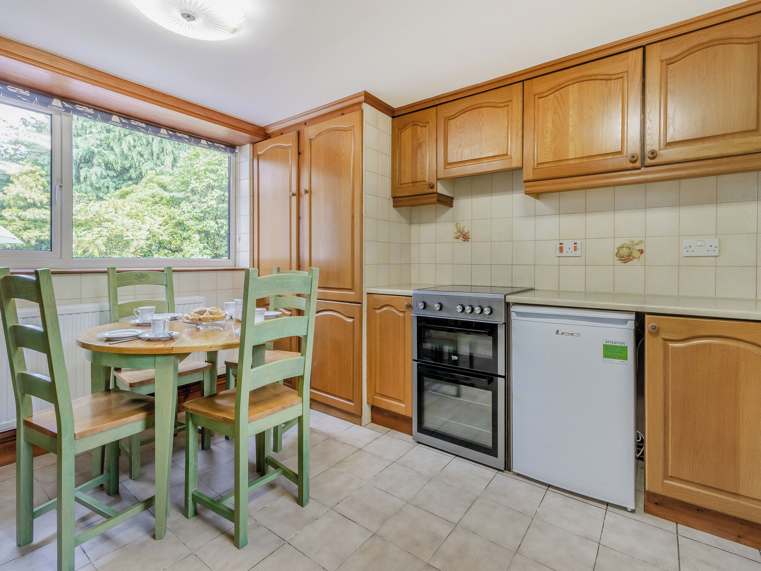 A kitchen with wooden cabinets, a dining table with chairs, a stove, an oven, and a dishwasher.