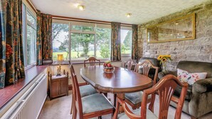 Un espace repas comprenant une grande table, des chaises, une cheminée et un mur en pierre.
