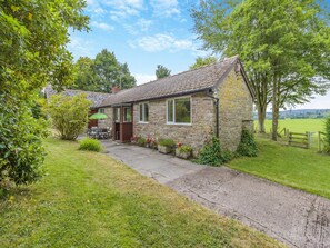A stone cottage with a garden, a patio with a table and chairs, and a view of the countryside. - 3 bedroom accommodation in Kingswood, near Kington (Kingswood, near Kington)