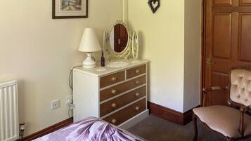A bedroom with a bed, dresser, mirror, chair, and a door.