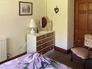 A bedroom with a bed, dresser, mirror, chair, and a door. - 3 bedroom accommodation in Kingswood, near Kington (Kingswood, near Kington)