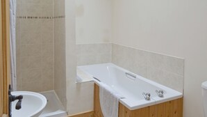 Et badeværelse med badekar, vask og bruseniche.