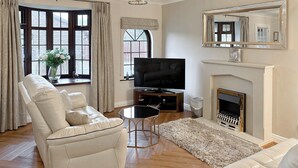 Una sala de estar con un sofá de cuero blanco, una mesa de centro negra y una chimenea.