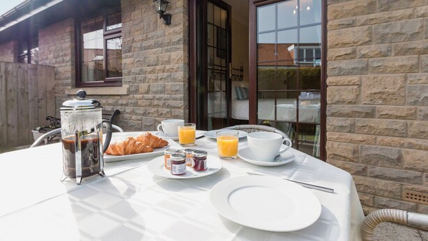 Una mesa de desayuno servida con cruasanes, jugo, café y mermelada.