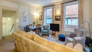 Una sala de estar con un sofá, sillones, un televisor y una mesa de comedor.