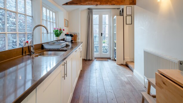 Una cocina moderna con techo de vigas de madera, un ventanal grande y un lavabo con grifo.