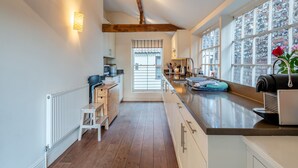 Una cocina moderna con vigas de madera, un amplio ventanal con vistas y una cafetera integrada.