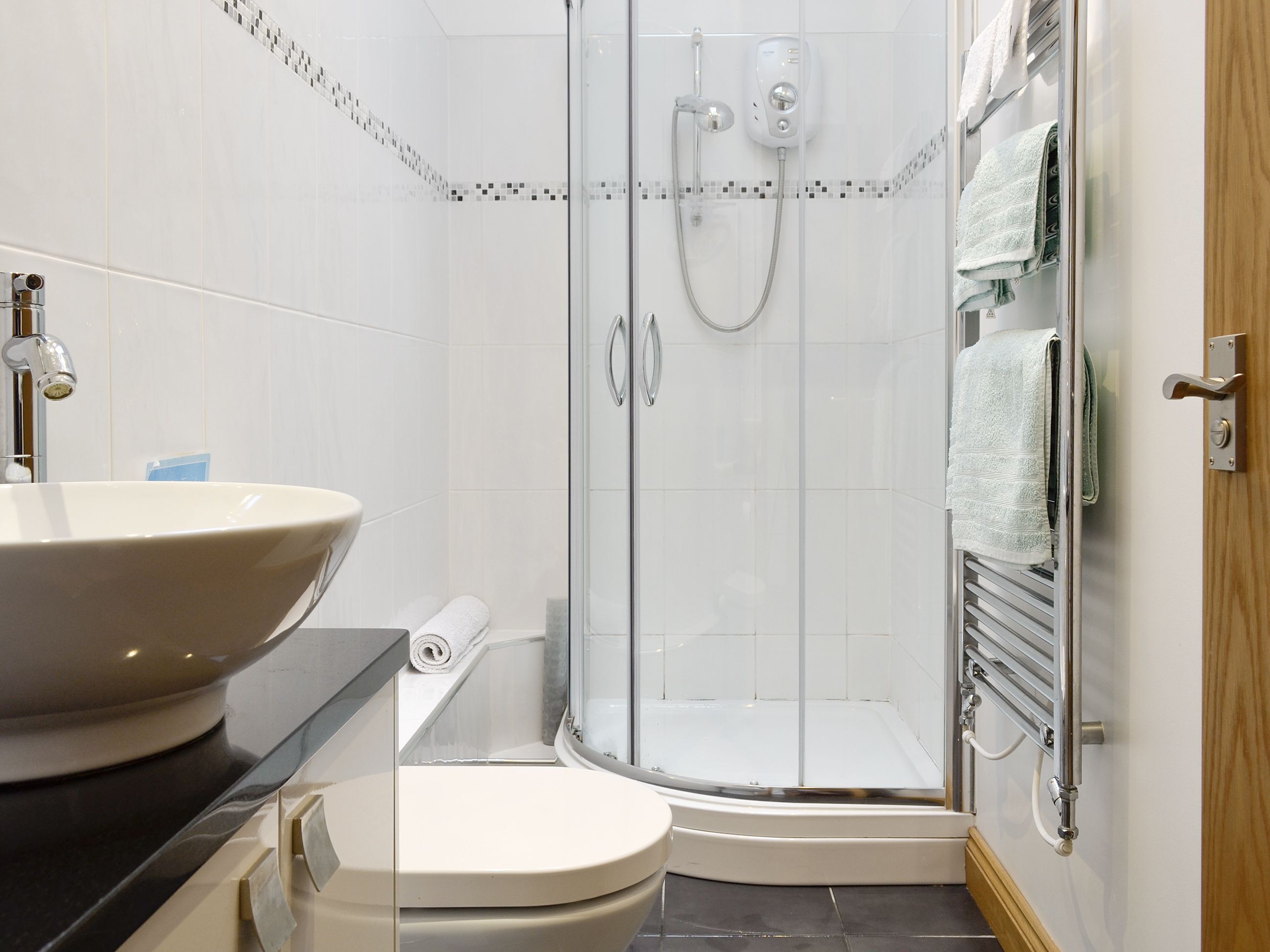 A bathroom with a sink, toilet, shower, and towel rack.