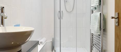 A bathroom with a sink, toilet, shower, and towel rack.