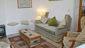 Uma sala de estar com sofá, poltronas, mesa de centro e lareira.