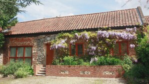 A rustic brick house with a tiled roof, a wooden door, and a small set of steps leading to the entrance. - The Street Farm Barn (Costessey, Norwich)