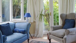 Une pièce avec un canapé bleu, un fauteuil à motifs et une plante en pot.