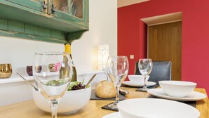 Een eettafel gedekt met wijnglazen, een saladekom, een brood en een fles wijn.