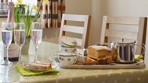 A dining table with a polka dot tablecloth, a bottle of wine, glasses, a floral teapot, a teacup, a teapot, a slice of cake, and a small plant. - All on the Ground Floor: 
Open plan living space. (near Kirkbymoorside)