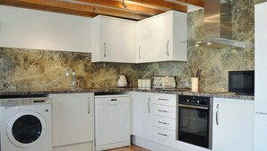 A modern kitchen with white cabinets, a built-in washing machine, a dishwasher, an oven, and a microwave. - All on the Ground Floor: 
Open plan living space. (near Kirkbymoorside)