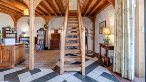 Un escalier en bois dans une pièce au style rustique, avec des étagères et un sol à carreaux.
