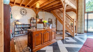 Une pièce spacieuse avec un bureau en bois, des étagères, une horloge et un escalier.