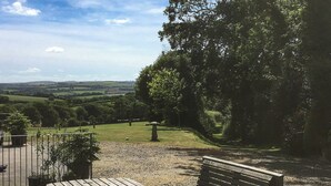 A wooden table and bench set outdoors with a view of a grassy area and trees. - Lower Shippen - 23493 (North Petherwin, near Launceston)