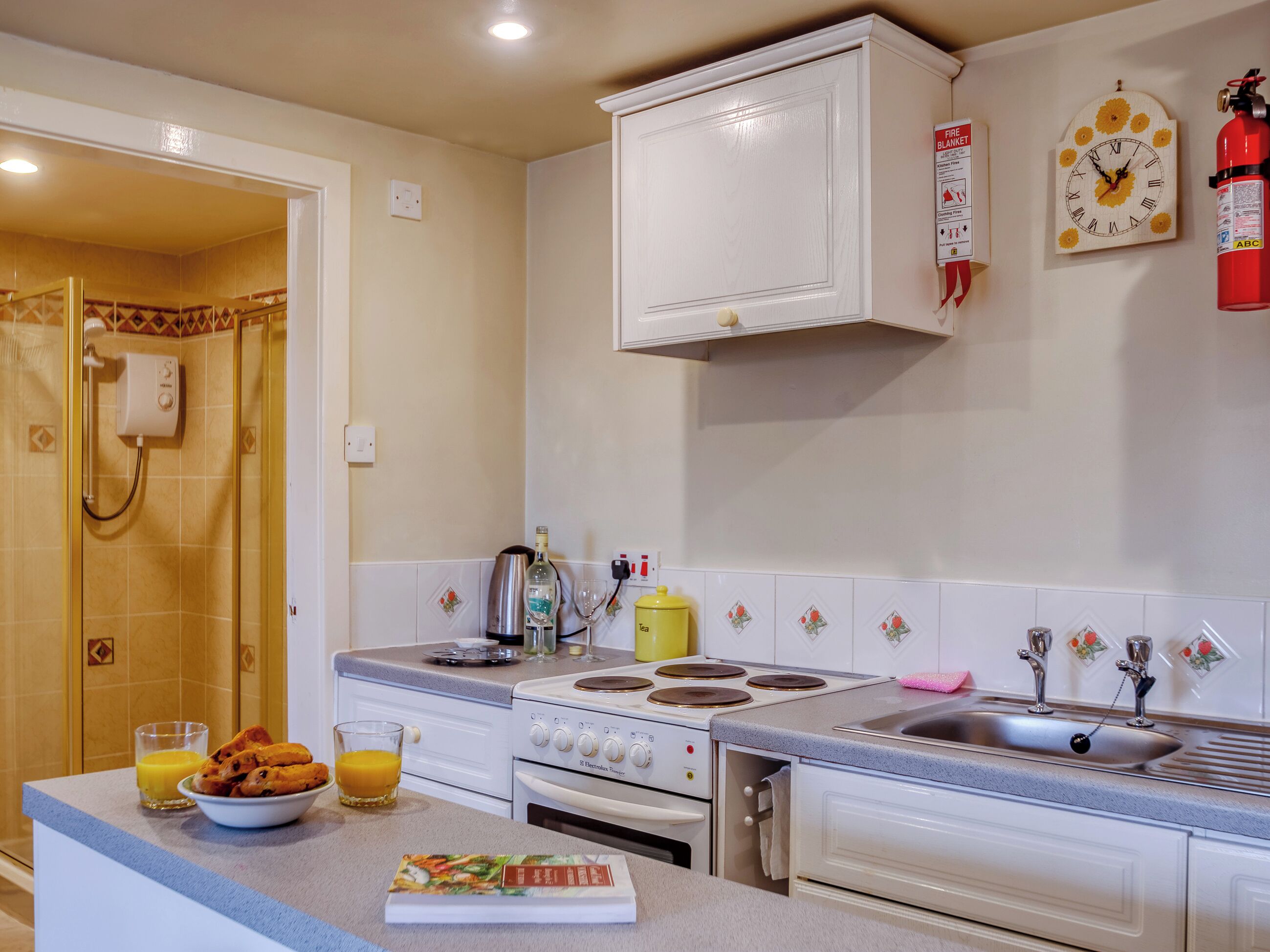 A kitchen with a stove, sink, and a clock on the wall.