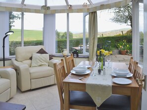 A conservatory with a dining table set for four, a sofa, and a view of the garden. - 1 bedroom accommodation in Dalton-in-Furness (Dalton-in-Furness)
