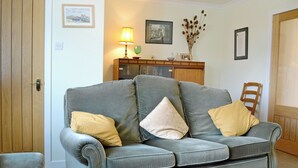 A living room with a grey sofa, two yellow cushions, a wooden cabinet, and a framed picture on the wall. - 2 bedroom accommodation in Benderloch near Oban (Benderloch near Oban)