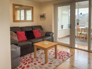 A living room with a dark leather sofa, a wooden coffee table, and a patterned rug. - 1 bedroom accommodation in Drumnadrochit (Drumnadrochit)
