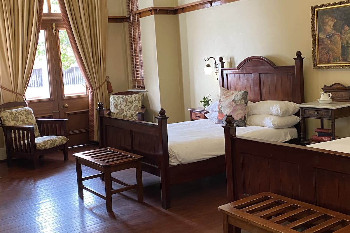 Une chambre à coucher de style traditionnel, avec un lit à baldaquin en bois, une table de chevet avec une lampe, une chaise et une petite table.