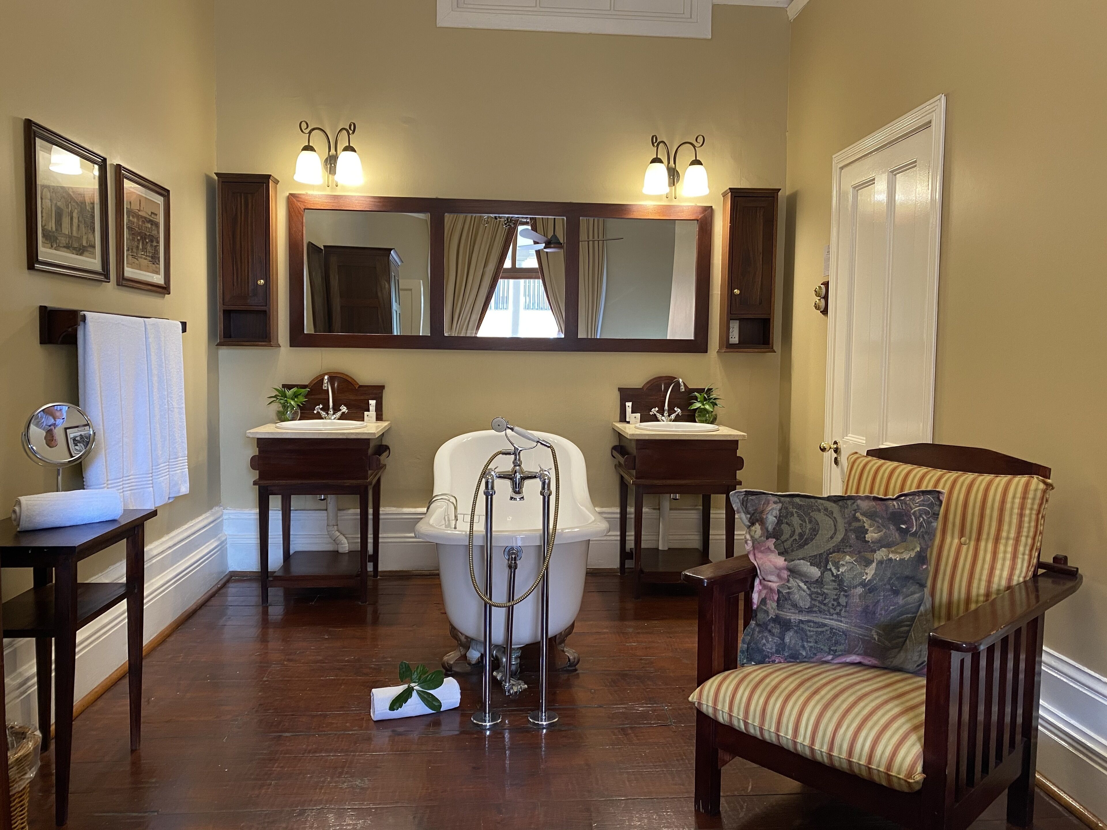 A bathroom with a bathtub, two sinks, a mirror, and a chair.
