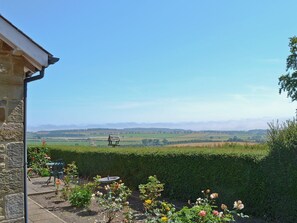 A garden with a view of distant hills, a wooden bench, and a table. - 3 bedroom accommodation in Alnwick (Alnwick)