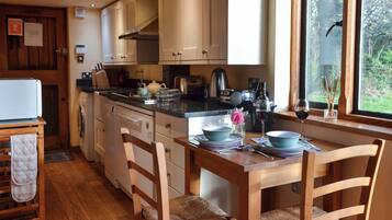 A kitchen with wooden cabinets, a dining table set for four, and a view of the outdoors through a window.