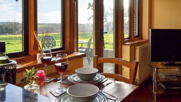 Una mesa de comedor dispuesta con cuencos, copas de vino y un jarrón con flores.