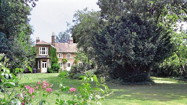 A large house with a well-maintained lawn and a large tree in the foreground. - 3 bedroom accommodation in Waxham (Waxham)