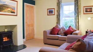 Una sala de estar acogedora con chimenea, un conjunto de sofás y una ventana con cortinas.