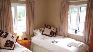 Habitación de hotel con dos camas, paredes color beige y un ventanal con cortinas.