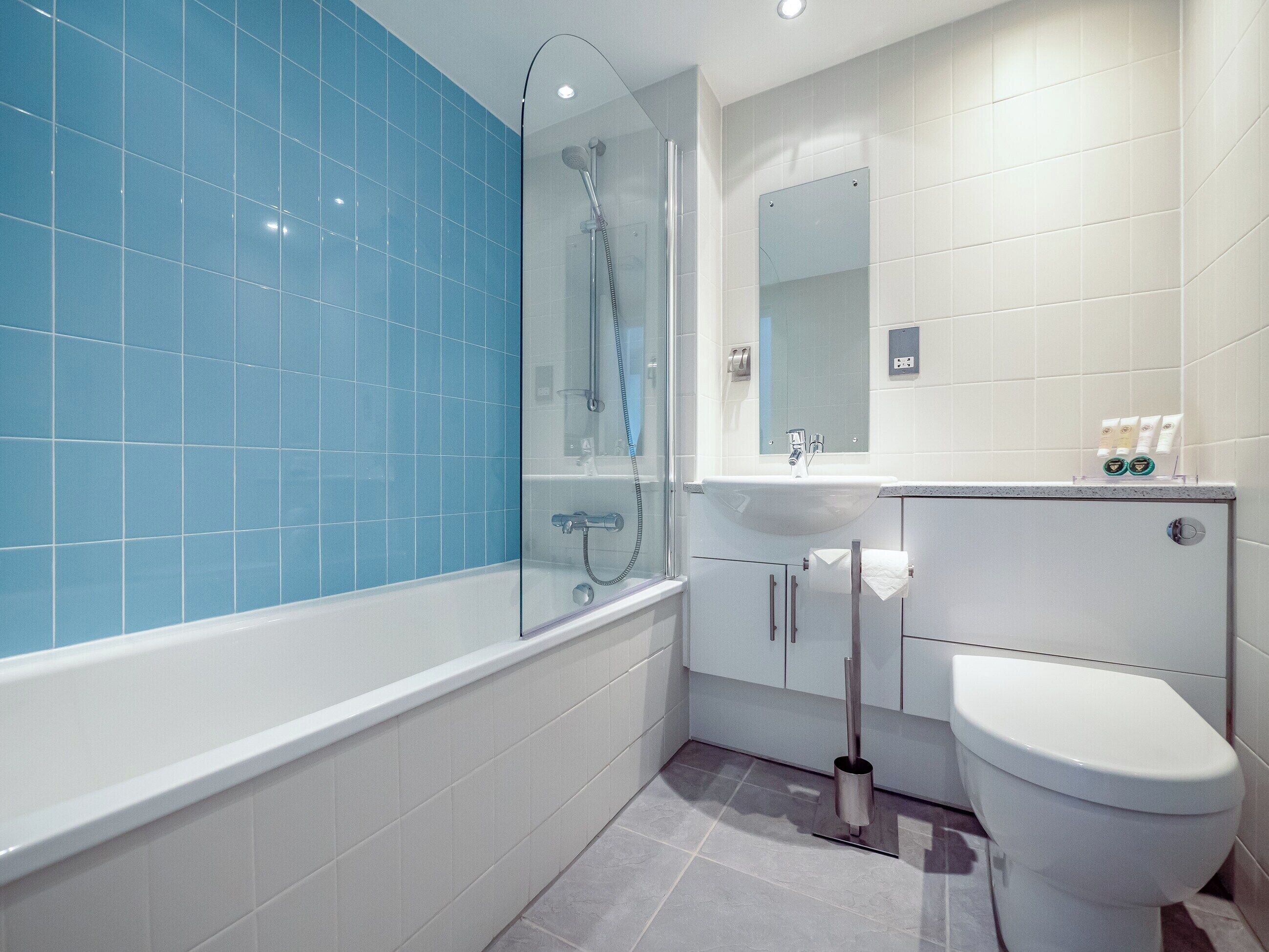 A modern bathroom with a glass-enclosed shower, a white sink, and a toilet.