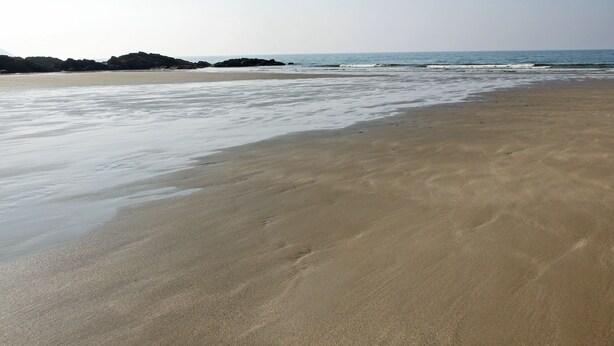 Una playa con arena y olas suaves.