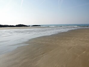 A beach with a wide sandy shore and gentle waves.