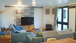 Una sala de estar con televisor, sofá y chimenea.