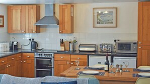 Una cocina moderna con armarios de madera, estufa a gas, microondas y una mesa de comedor lista para dos personas.