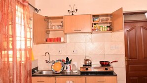 A kitchen with wooden cabinets, a sink, a kettle, and a stove. - Sherry Homes Zuri Studio (Nairobi)
