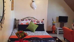 A bedroom with a bed, a bedside table, a TV, and a chair. - Sherry Homes Zuri Studio (Nairobi)