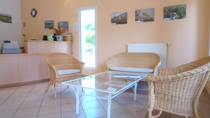 A reception area with wicker furniture, a glass table, and framed pictures on the wall. - VVF La Salvetat sur Agoût (La Salvetat-sur-Agout)