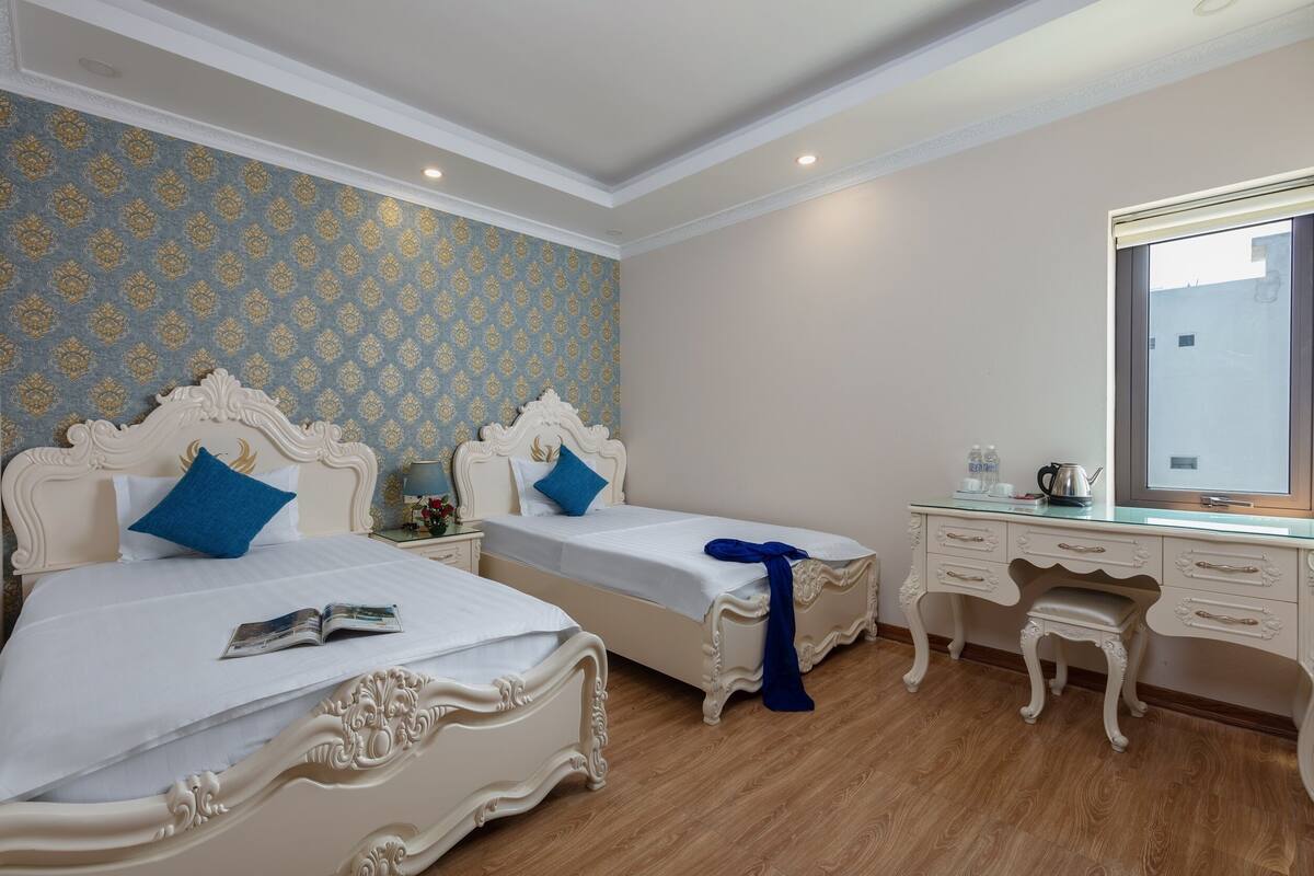 A hotel room with two beds, a dresser, and a mirror.
