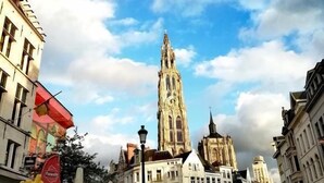 Una plaza histórica con una torre destacada, calles empedradas y arquitectura europea tradicional.