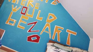 A blue wall with the text "There would be no life without art" in yellow and red letters.
