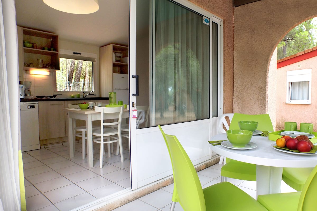 A dining area with a table set for two, chairs, and a fruit bowl.