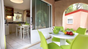 A dining area with a table set for two, chairs, and a fruit bowl. - VVF Montagnac Hérault (Montagnac)