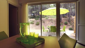 A room with a table set for two, a green chair, and a yellow umbrella outside. - VVF Montagnac Hérault (Montagnac)