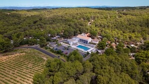 An aerial view of a resort with a swimming pool, surrounded by dense forest and a vineyard. - VVF Montagnac Hérault (Montagnac)