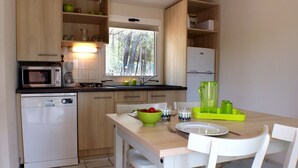 A compact kitchen with a dishwasher, microwave, and a small dining table with chairs. - VVF Montagnac Hérault (Montagnac)